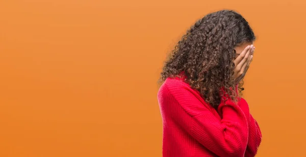 若いヒスパニックの女性は泣きながら手で顔を覆っている悲しそうな表情で赤いセーターを着ています うつ病の概念 — ストック写真