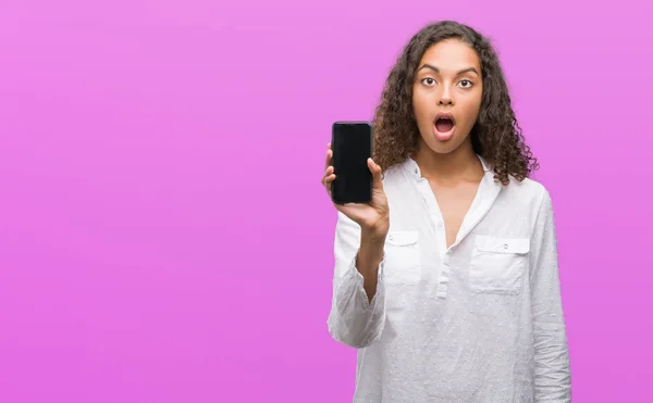 Young Hispanic Woman Using Smartphone Scared Shock Surprise Face Afraid — Stock Photo, Image