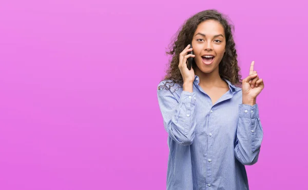 年轻的西班牙裔妇女使用智能手机惊讶于一个想法或问题指向手指与快乐的脸 — 图库照片