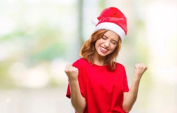 若い美しい女性非常に幸せと興奮の腕を上げ 勝者のジェスチャを行うクリスマス帽子をかぶっている孤立した背景に笑みを浮かべて 成功のために叫んで お祝いのコンセプト — ストック写真