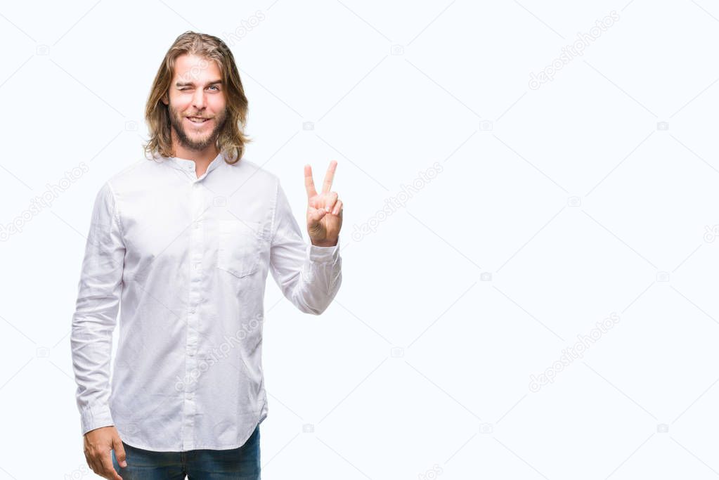 Young handsome man with long hair over isolated background smiling with happy face winking at the camera doing victory sign. Number two.