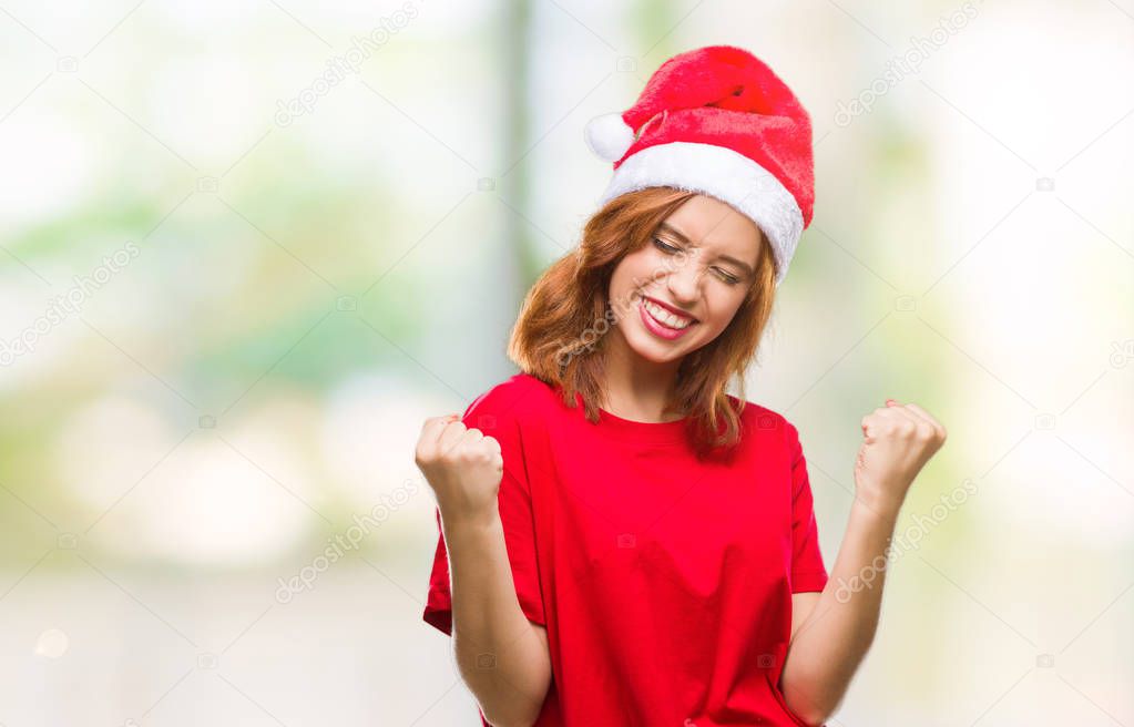 Young beautiful woman over isolated background wearing christmas hat very happy and excited doing winner gesture with arms raised, smiling and screaming for success. Celebration concept.