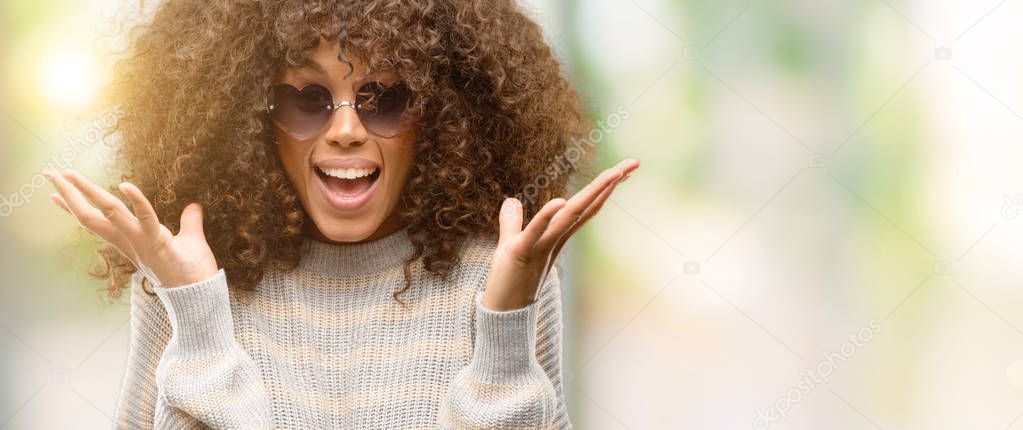 African american woman wearing a stripes sweater very happy and excited, winner expression celebrating victory screaming with big smile and raised hands