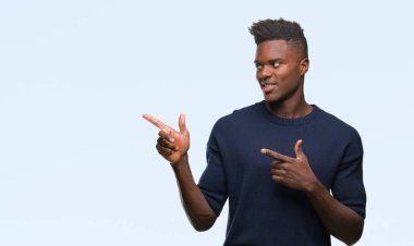 Gülümseyen ve iki elleri ve parmakları ile tarafına işaret kamera bakarak izole arka plan üzerinde genç Afro-Amerikan adam.