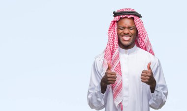 Geleneksel keffiyeh izole arka kolları olan başarı için heyecan üzerinde giyen genç Arapça Afrika adam zafer kutluyor gülümseyen kaldırdı. Kazanan kavramı.