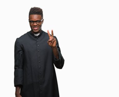 Genç Afro-Amerikan rahip adam gösterilen ve parmakları ile işaret izole arka plan üzerinde ikincisi ise kendinden emin ve mutlu gülümseyerek.