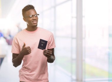 Ok işareti, başparmak ile parmak, mükemmel işareti yapıyor kocaman bir gülümseme ile Alman pasaportu mutlu tutan genç Afro-Amerikan adam