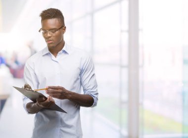 Bir clipboarad kendinden emin bir ifade ile acımak yüz ciddi düşünüyorum tutan genç Afro-Amerikan adam