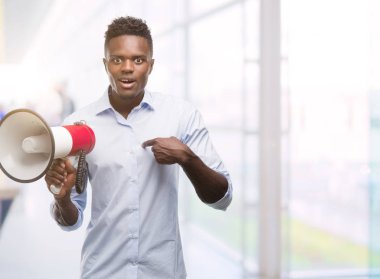 Megafon sürpriz yüz işaret parmağı kendisine tutan genç Afro-Amerikan adam