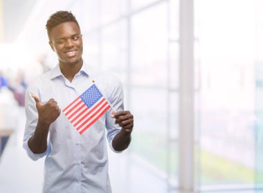 El ve parmak ile yukarı dönük mutlu yüz gülümseyen ile ABD bayrağı tutan genç Afro-Amerikan adam