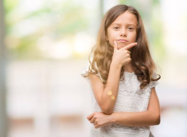 Esmer İspanyol kız emin çapraz kollar ve çeneme kaldırdı el ile gülümseme ile kameraya bakıyor. Pozitif düşünce.