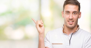 Yakışıklı genç casual adam beyaz t-shirt el ve parmak ile tarafına işaret çok mutlu giyiyor