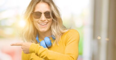 İşaret parmağı ile uzak yan kulaklık ile genç güzel kadın