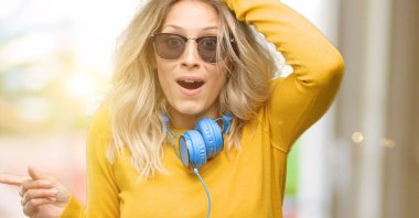 İşaret parmağı ile uzak yan kulaklık ile genç güzel kadın