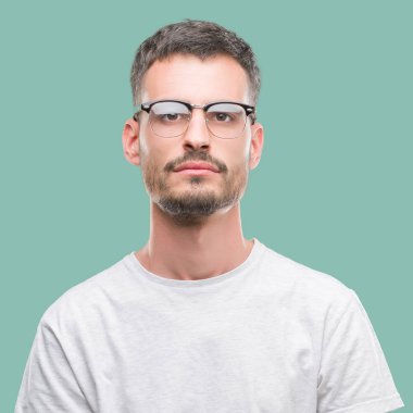 Genç yetişkin adam yüzünde ciddi bir ifade ile dövme. Basit ve doğal kameraya bakıyor.