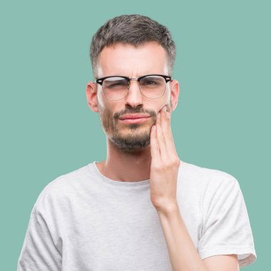 Genç yetişkin adam acı ifadesi ile el ile ağız diş ağrısı veya dişlerde dişlerle ilgili hastalık nedeniyle dokunmadan dövme. Diş hekimi kavramı.