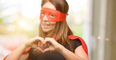 Elle kalp şekli sağlıklı ifade ve evlilik sembol kırmızı maske ve cape mutlu gösteren sevgi giyen orta yaş süper kahraman kadın