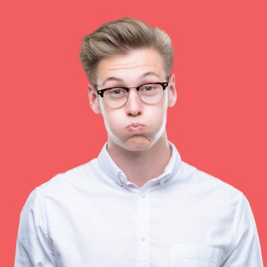 Komik surat ile yanakları şişirme genç yakışıklı sarışın adam. Ağız ile hava, deli ifade şişirilmiş.