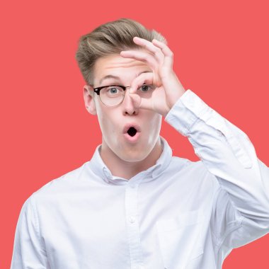 Sürpriz yüz, göz parmaklarının arasından seyir ile ok jest yapan genç yakışıklı sarışın erkek şok. İmansız ifade.