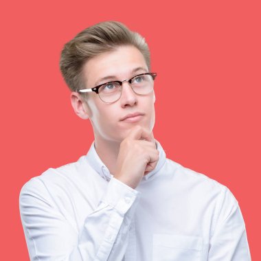 Çene düşünme hakkında soru, dalgın ifade üzerine el ile genç yakışıklı sarışın adam. Düşünceli yüzüyle gülümsüyor. Şüphe kavramı.