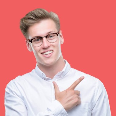 Genç yakışıklı sarışın adam neşeli bir gülümseme ile el ve parmak kadar kameraya bakarak yüzündeki mutlu ve doğal ifade ile yan ile işaret eden yüz.