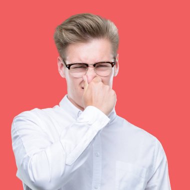 Genç yakışıklı sarışın adam bir şey pis ve iğrenç kokulu, dayanılmaz koku, umutla parmaklarıyla burnuna. Kötü kokuyor kavramı.