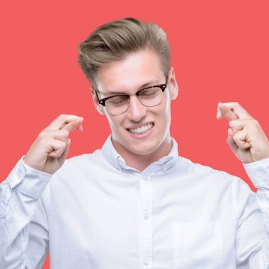 Umut ve gözleri kapalı geçiş parmaklarıyla gülümseyen genç yakışıklı sarışın adam. Şans ve batıl kavramı.