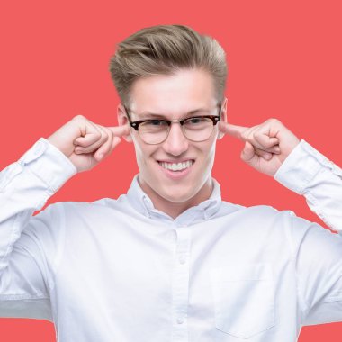 Yüksek sesle müzik gürültü rahatsız ifade parmaklarıyla kulaklarıyla kapsayan genç yakışıklı sarışın adam. Sağır kavramı.