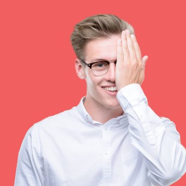 Genç yakışıklı sarışın adam yüz ve sürpriz duygu kendinden emin gülümseme ile el ile bir göz kapsayan.