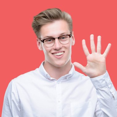 Gösterilen ve parmakları ile işaret genç yakışıklı sarışın adam kendinden emin ve mutlu gülümseyerek süre beş numara.