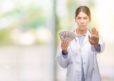 Açık eliyle dur işareti ile ciddi ve kendine güvenen ifade, savunma jest yapıyor dolar tutan genç İspanyol doktor kadın