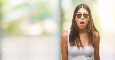 Genç güzel İspanyol korkuyor ve şok sürpriz ifade, korku ve heyecan yüz ile güneş gözlüğü takıyor.