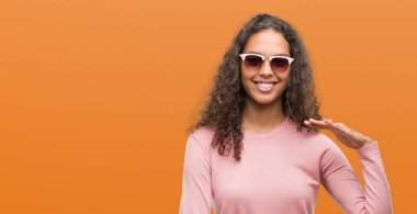 Güzel genç İspanyol kadın ile büyük ve büyük boy işaret, ölçü birimi sembol gösteren el el hareketi güneş gözlüğü takıyor. Kameraya bakarak gülümsüyordu. Ölçüm kavramı.