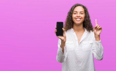 Bir fikir ya da soru işaret parmağı gülen yüz, bir numara ile Smartphone sürpriz kullanan genç İspanyol kadın