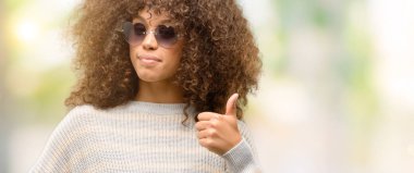 Ok işareti, başparmak ile parmak, mükemmel işareti yapıyor kocaman bir gülümseme ile mutlu bir çizgili süveter giyen Afrikalı-Amerikalı kadın