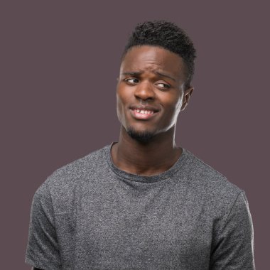 Görünümlü yan ve dik dik bakma uzağa düşünce gülümseyen gri t-shirt giyen genç Afro-Amerikan adam.