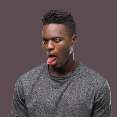 Gri t-shirt yapışma dil giyen genç Afro-Amerikan adam out komik ifade ile mutlu. Duygu kavramı.