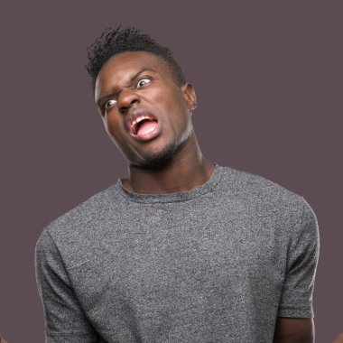 Gri t-shirt çılgın ve kızgın bağırarak ve agresif ifade ve silah kaldırdı bağırmaya giyen genç Afro-Amerikan adam. Hayal kırıklığı kavramı.