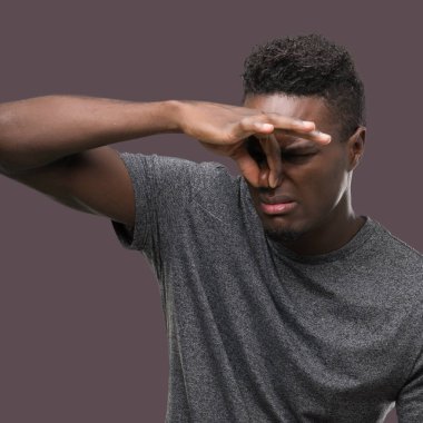 Gri t-shirt bir şey pis ve iğrenç kokulu, dayanılmaz koku, holding nefes parmak ile burun üzerinde giyen genç Afro-Amerikan adam. Kötü kokuyor kavramı.