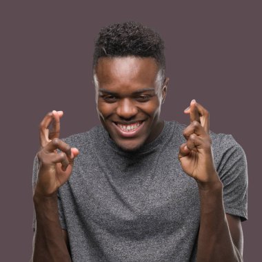 Gri gömlek gülümseyen geçiş parmakları ile umut ve gözleri kapalı giyen genç Afro-Amerikan adam. Şans ve batıl kavramı.