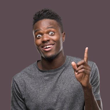 Gri t-shirt işaret parmağı ile başarılı fikir giyen genç Afro-Amerikan adam. Çıktıktan ve mutlu. Bir numara.