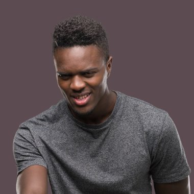 Tebrik ve konuksever dost sunan karşılıklı gülümseyen gri t-shirt giyen genç Afro-Amerikan adam. Başarılı iş.