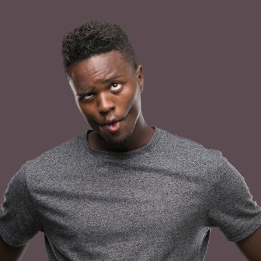 Gri t-shirt yapma balık yüz dudaklı, çılgın ve komik bir jest giyen genç Afro-Amerikan adam. Komik ifade.