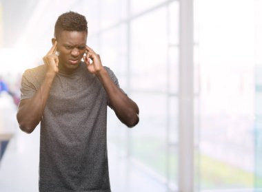 Gri t-shirt kapsayan kulakları parmakları ile yüksek sesle müzik gürültü rahatsız ifade ile giyen genç Afro-Amerikan adam. Sağır kavramı.