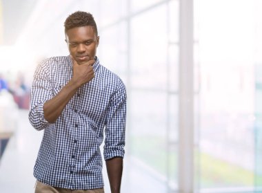 Emin çapraz kollar ve çeneme kaldırdı el ile gülümseme ile kameraya bakarak mavi gömlek giymiş genç Afro-Amerikan adam. Pozitif düşünce.