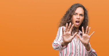 Şokta bağırarak güzel genç İspanyol kadın korkuyor ve korku ifade dur hareketi el ile ile çok korkmuş. Panik kavramı.