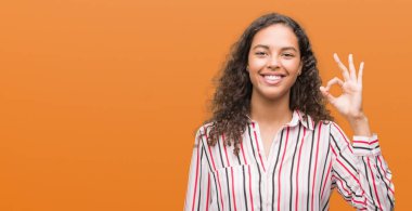 El ve parmak ile ok işareti yapıyor olumlu gülümseyen güzel genç İspanyol kadın. Başarılı ifade.