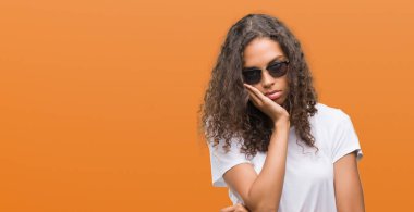 Düşünme seyir yorgun ve sıkılmış depresyon sorunları ile güneş gözlüğü takmış genç İspanyol kadın kolları geçti.