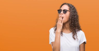 Genç İspanyol kadın güneş gözlüğü takıyor el ağzıyla kapsayan yorgun esneme sıkılmış. Restless ve uyku hali.