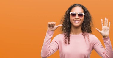 Güzel genç İspanyol kadın ve parmak altıncı ile gülümseyen ise kendinden emin ve mutlu yukarıyı gösteren güneş gözlüğü takıyor.